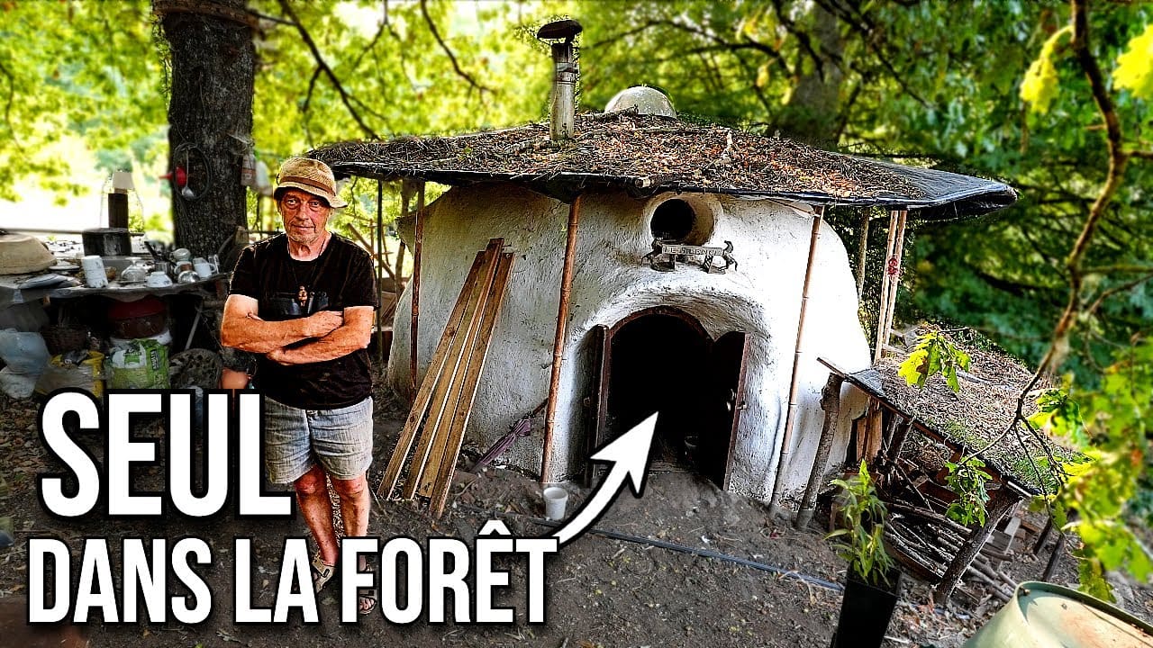 Un homme de 72 ans devant son habitation en terre et bois au milieu de la forêt